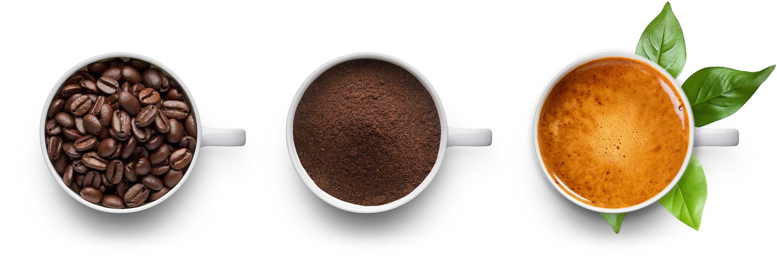 Tre tazzine riprese dall'alto. La tazzina a sinistra contiene caffè in grani, la tazzina centrale caffè macinato e la tazzina a destra un caffè con crema e sullo sfondo, sotto la tazzina ci sono delle foglie.